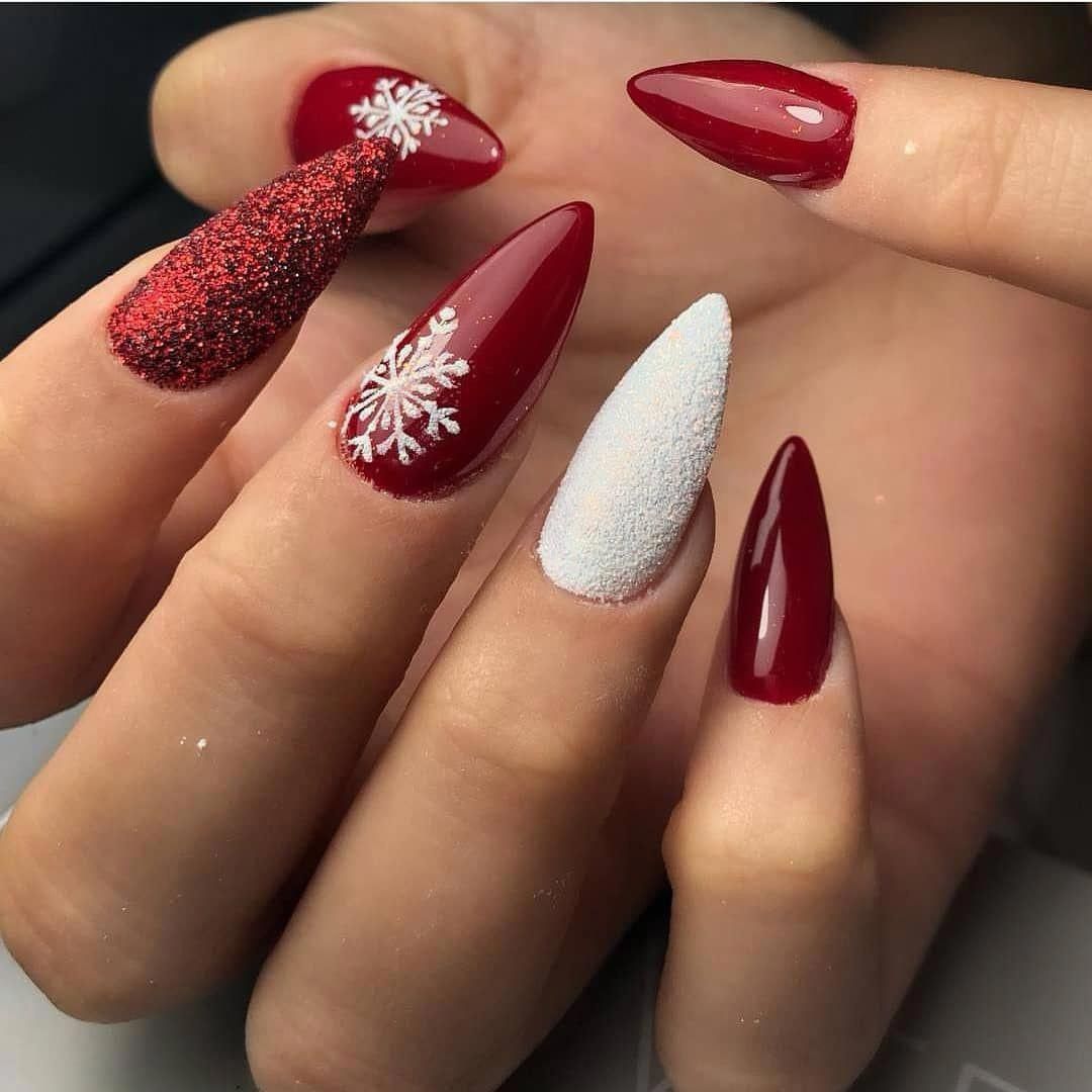 Photo d'ongles rouge avec un ail-art flocon, paillettes et neige