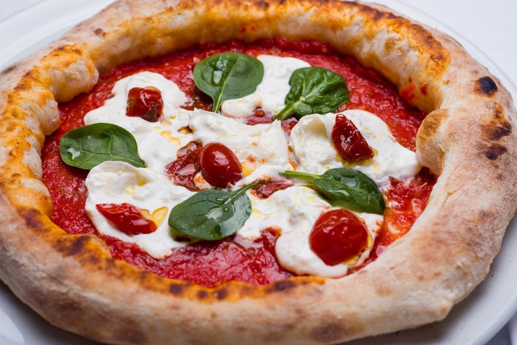 Pizza Margherita avec une base de tomate, mozzarella fondante et feuilles de basilic frais