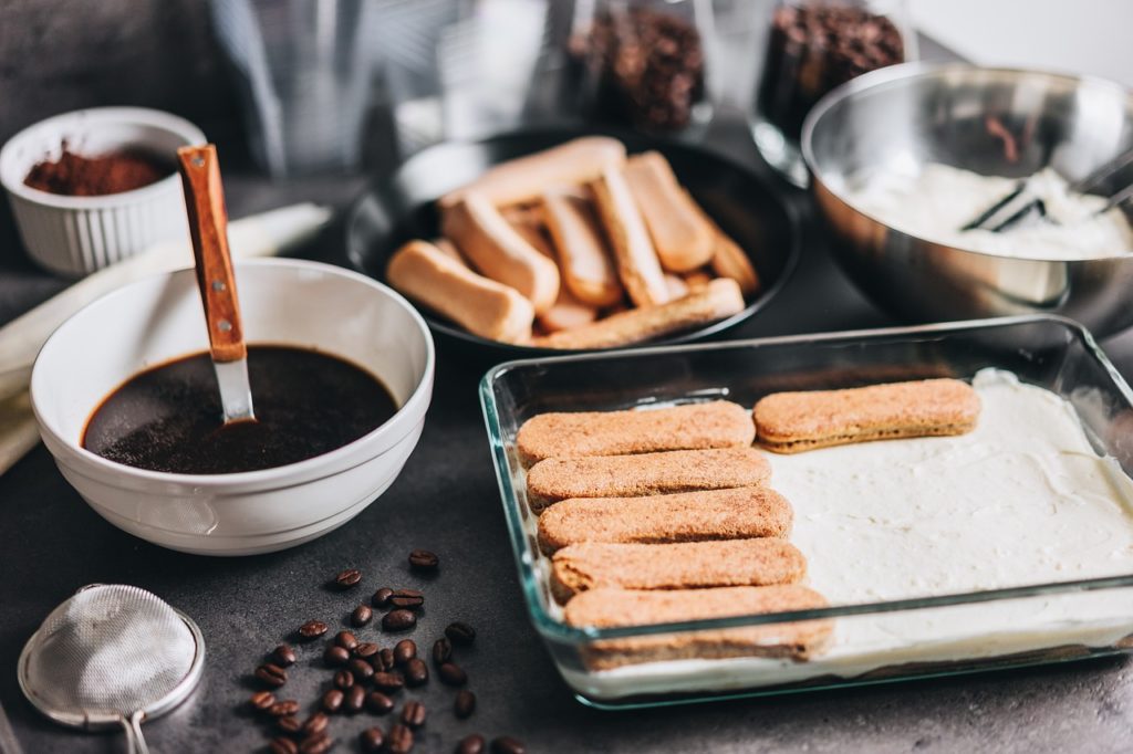 Préparation de tiramisu avec des biscuits imbibés de café, du mascarpone crémeux et du cacao en poudre